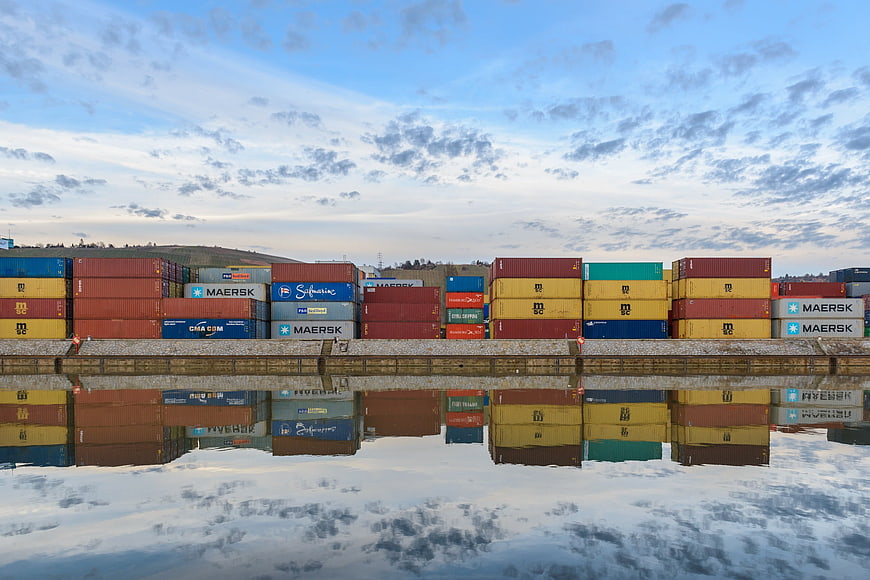 Colorful Shipping Containers Reflected in Calm Water at Port