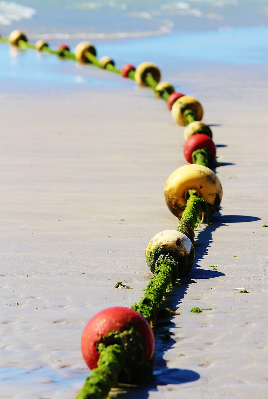 Colorful buoys on rope along sandy beach shoreline