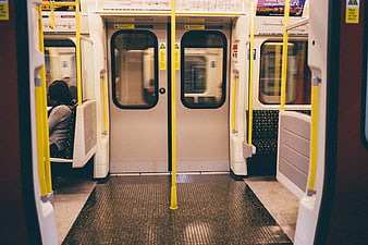 Interior of a subway car with yellow poles and doors