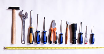 Flat lay of assorted hand tools and measuring tape on white background