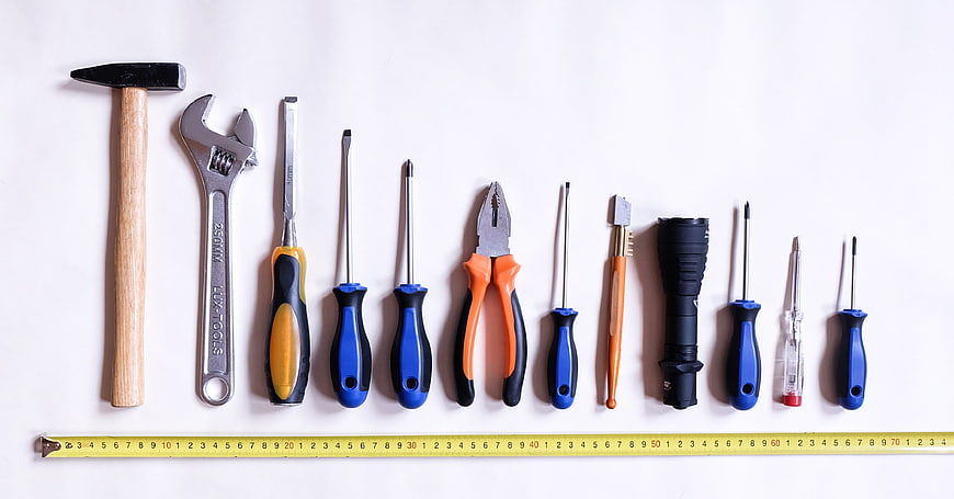 Flat lay of assorted hand tools and measuring tape on white background