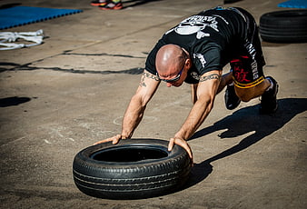Athlete performing tire push workout in outdoor functional training gym