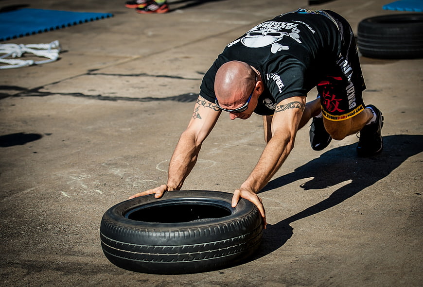 Athlete performing tire push workout in outdoor functional training gym