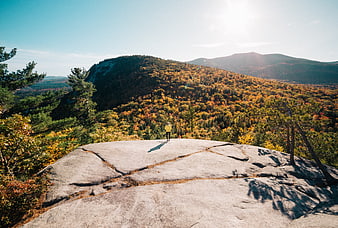 Hiker on rocky summit overlooking autumn mountain forest