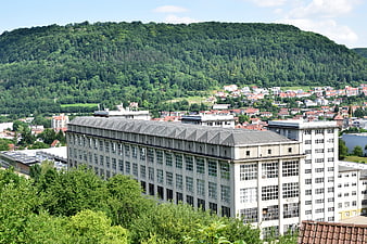 Large industrial building with forested mountain backdrop