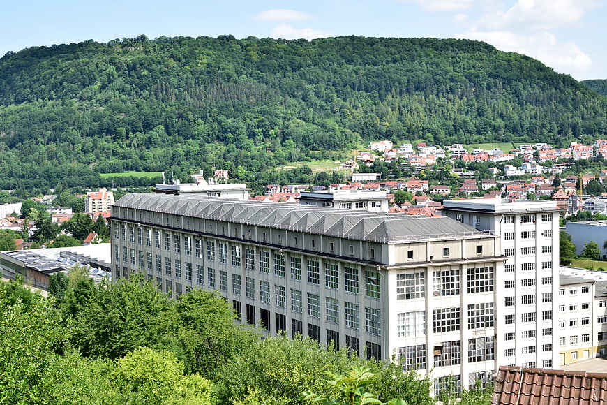 Large industrial building with forested mountain backdrop