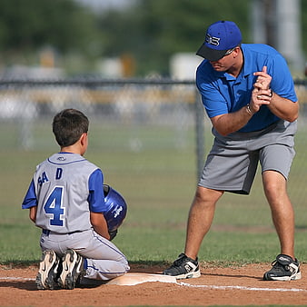 Baseball Coach Teaching Young Player on Field