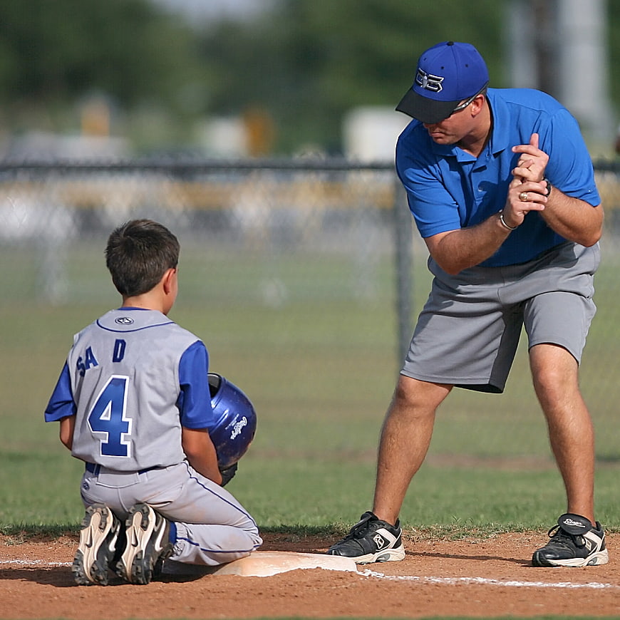 Baseball Coach Teaching Young Player on Field