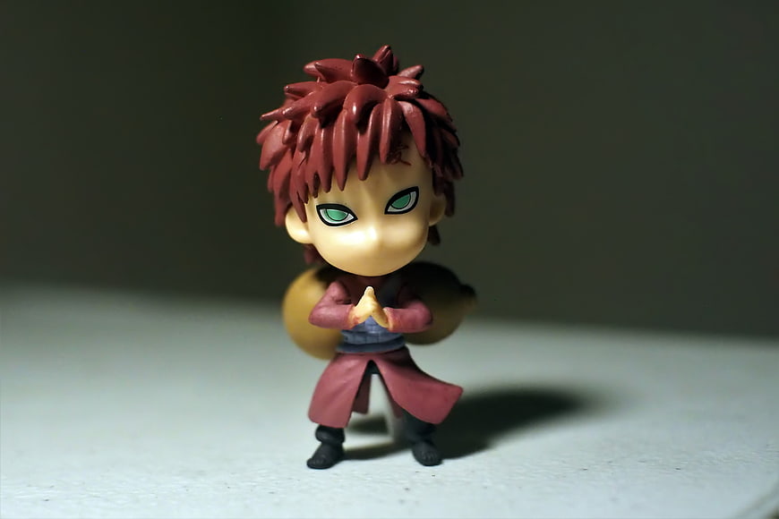 Chibi Naruto figurine with red hair and green eyes on a gray background