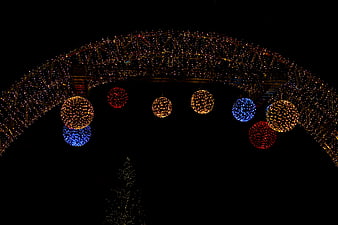 Festive Christmas Arch with Hanging Light Ornaments at Night