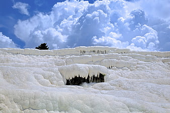 White travertine terraces with icicles under blue sky