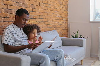Father and daughter reading a book together on a sofa