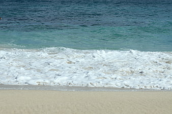Foamy Ocean Waves Washing Over Sandy Beach Shoreline