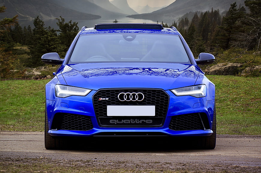 Front View Blue Audi RS6 Avant On Gravel Road With Mountain Lake Background