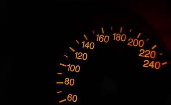 Illuminated Car Speedometer Dial With Orange Numbers On Black Background