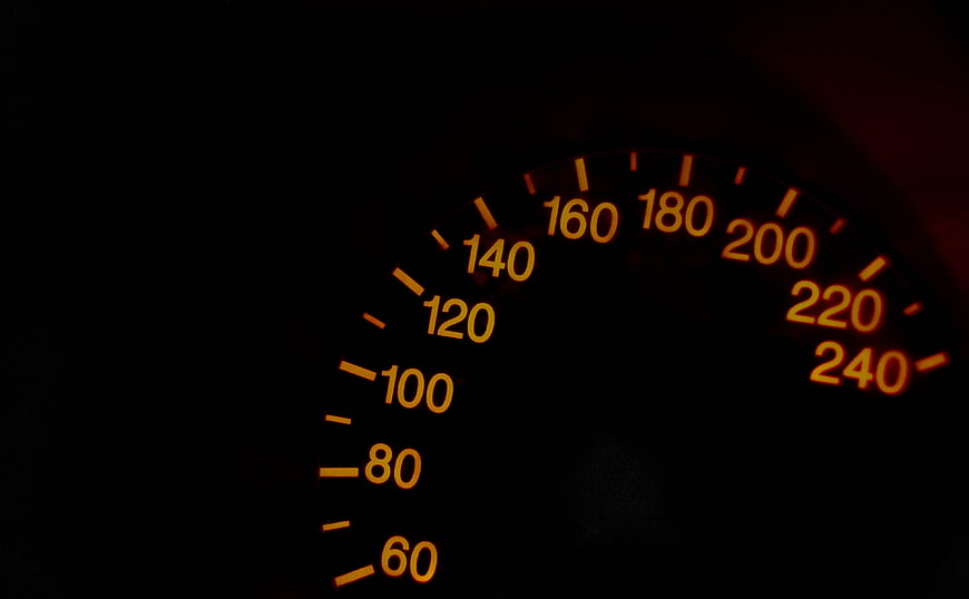 Illuminated Car Speedometer Dial With Orange Numbers On Black Background