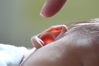 Close-up of baby ear with finger gently touching
