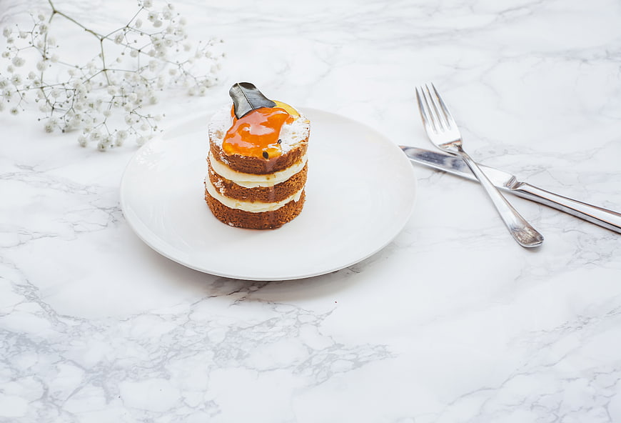 Mini layered cake with caramel glaze on white marble table