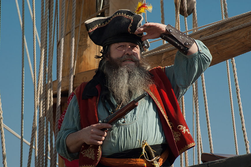 Bearded Pirate Costume Man Holding Pistol On Sailboat Rigging