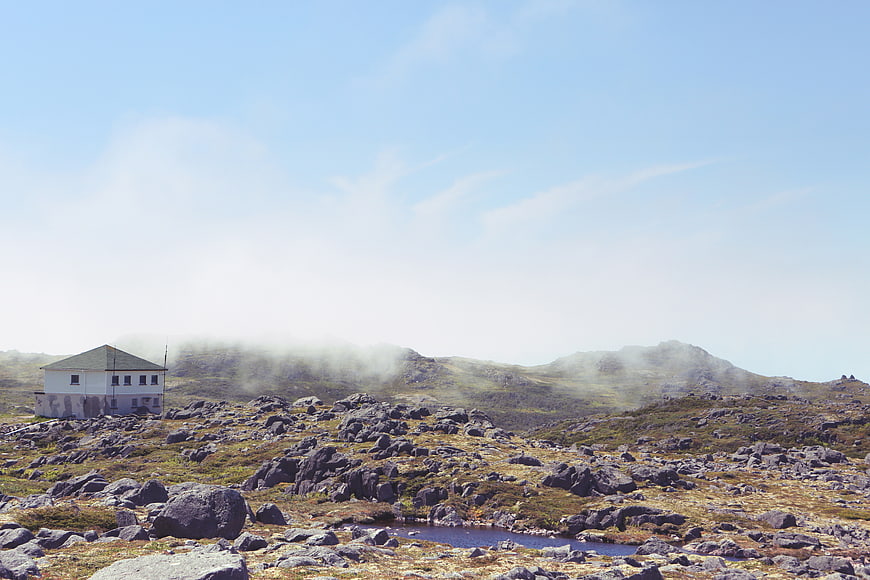 White Cabin in Rocky Mountain Landscape with Mist