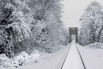 Snow-covered railway tracks leading to a bridge in winter