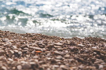 Close-up of pebbles on a beach with sparkling ocean background