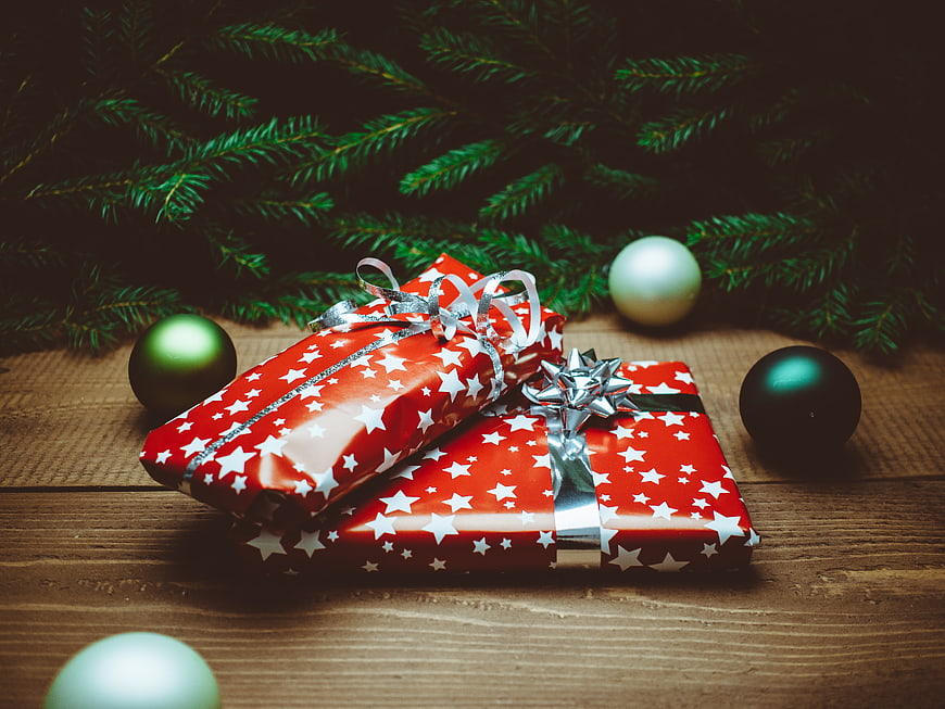 Christmas gifts wrapped in red star paper with ornaments