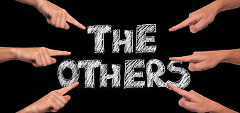 Hands pointing at the words THE OTHERS on black background