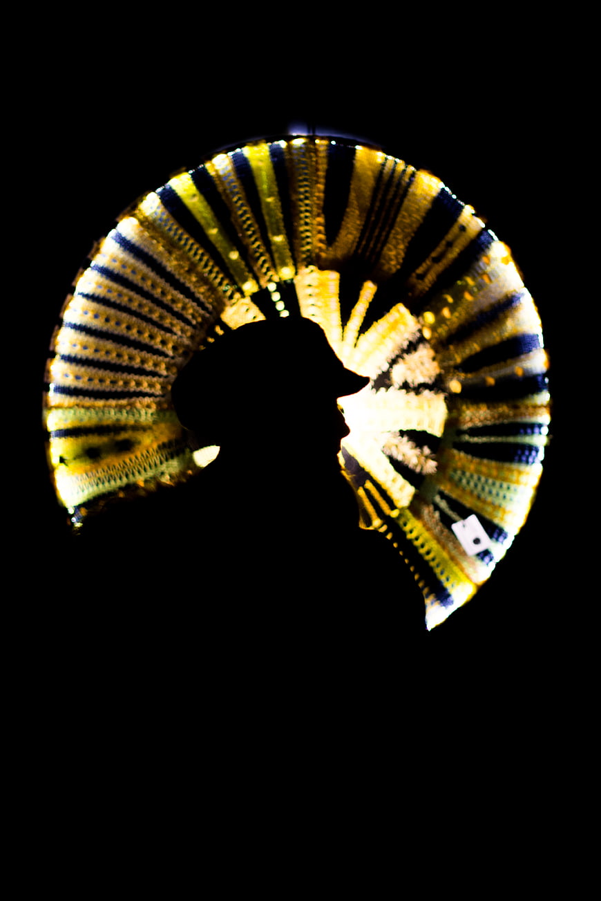 Silhouette of woman wearing colorful woven hat against black background