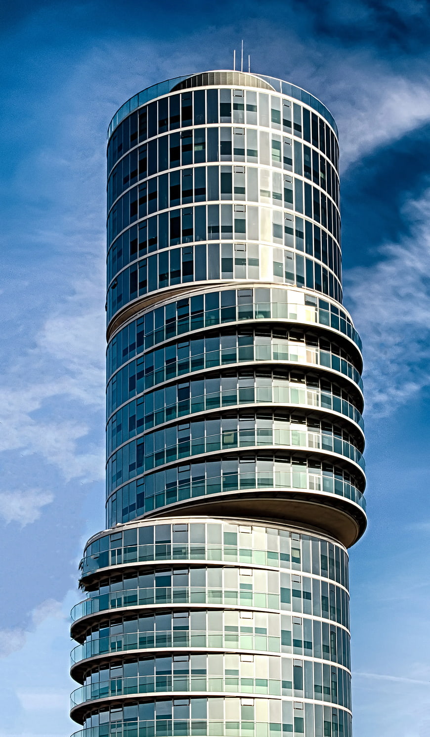 Modern Twisted Glass Skyscraper Against Blue Sky