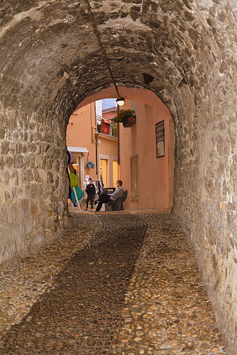 Cobblestone alleyway through stone arch in Malcesine, Italy