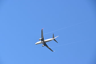 Commercial Airplane Flying in Blue Sky with Contrails