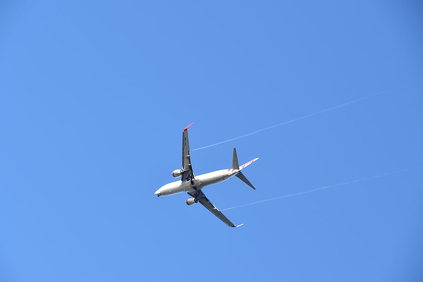 Commercial Airplane Flying in Blue Sky with Contrails