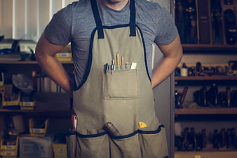 Craftsman in workshop wearing apron with tools