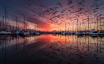 Dramatic Sunset Reflection Over Sailboats in Harbor