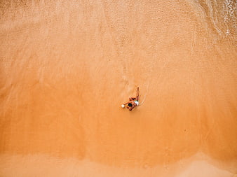Aerial View of Man Relaxing on Sandy Beach