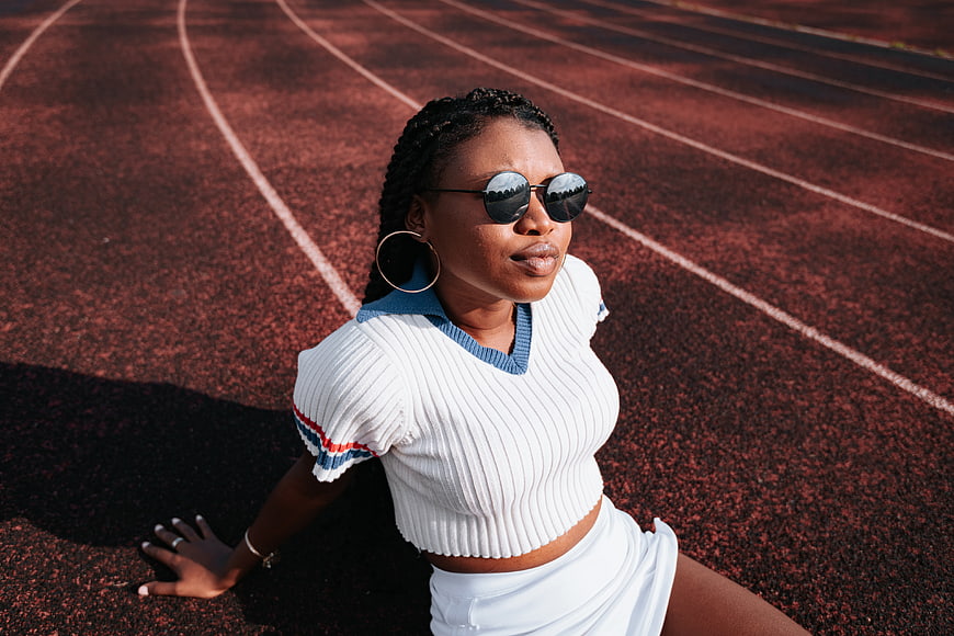 Stylish Black Woman in Sunglasses Sitting on Running Track