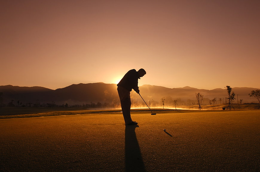 Silhouette of a Golfer Putting on a Golf Course at Sunset