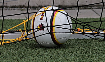 Soccer ball in goal net on artificial grass