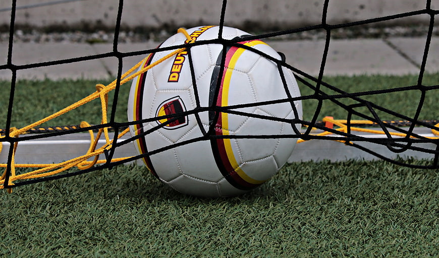 Soccer ball in goal net on artificial grass