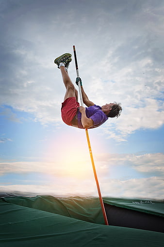 Male Athlete Performing Pole Vault Against Dramatic Sunset Sky