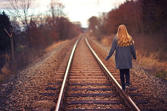 Woman Walking Away on Autumn Railway Tracks
