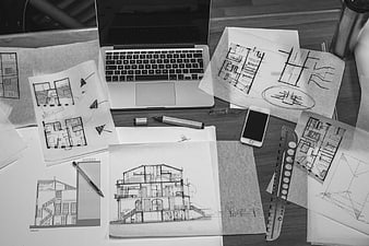 Black and white flat lay of architectural sketches and laptop