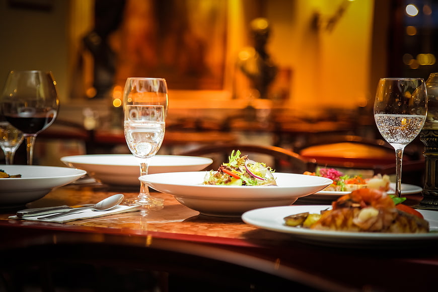 Elegant restaurant table setting with salad and wine glasses