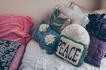 Colorful Decorative Pillows on Bed with Peace Text