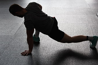 Man performing side plank exercise on gym floor