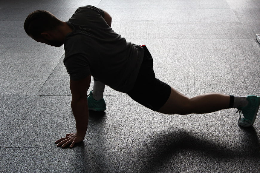 Man performing side plank exercise on gym floor
