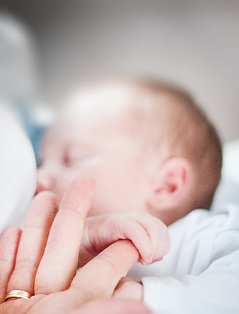 Close-up of newborn baby holding mother's finger