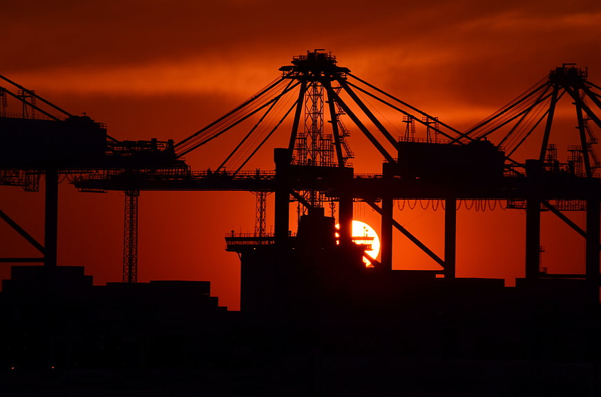 Silhouette of Port Cranes Against Vibrant Orange Sunset Sky