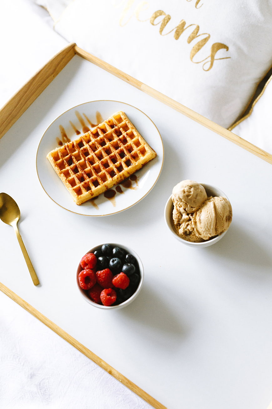 Overhead view of waffles with berries and ice cream on a tray